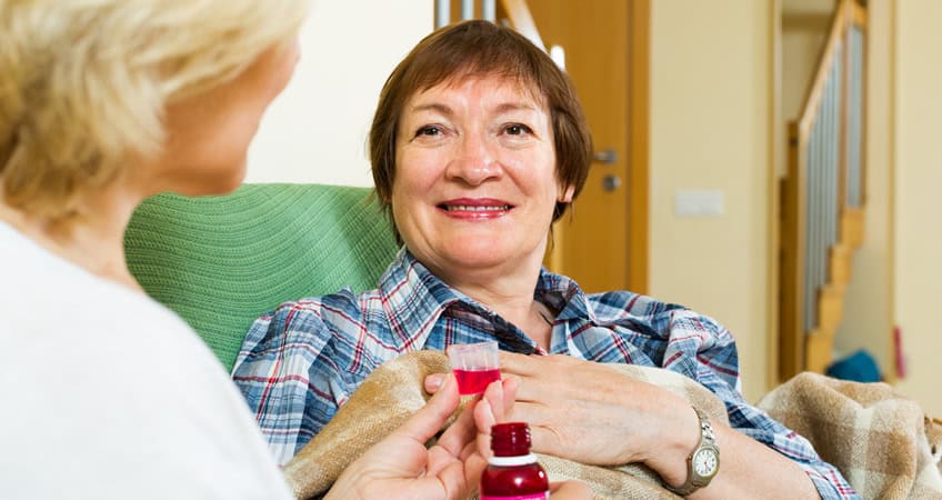 Older woman receiving medical care at home, showing support for Irish senior citizens.