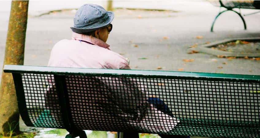Elderly woman enjoying a quiet moment on park bench, reflecting peace and well-being.
