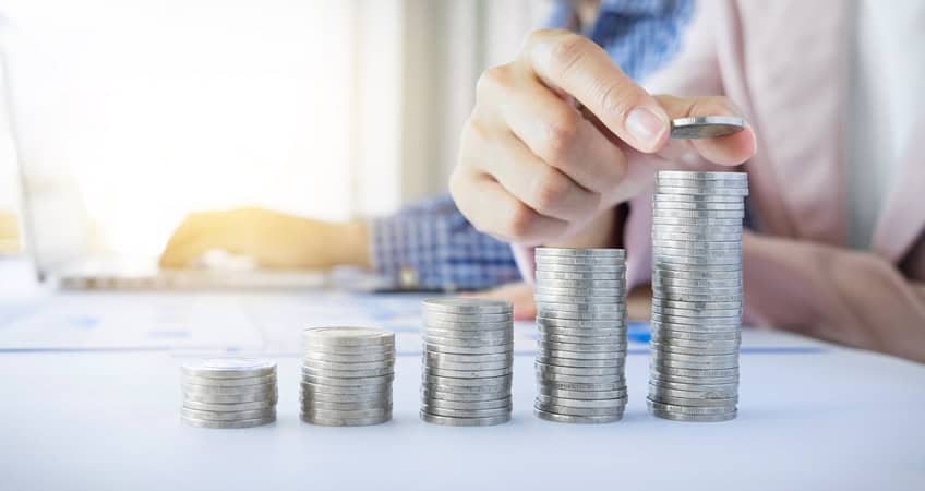 Alt text: Elderly person stacking coins, symbolising senior financial planning and economic security.
