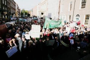 Crowd of senior citizens protesting with banners and placards at the Irish Senior Citizens Parliament.