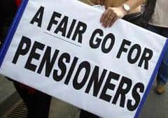 Active seniors holding a sign for fair pensions at a community event.