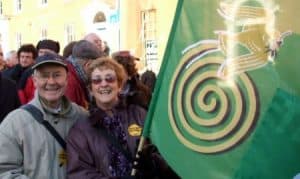 Happy seniors at Irish Senior Citizens Parliament holding colourful flag.