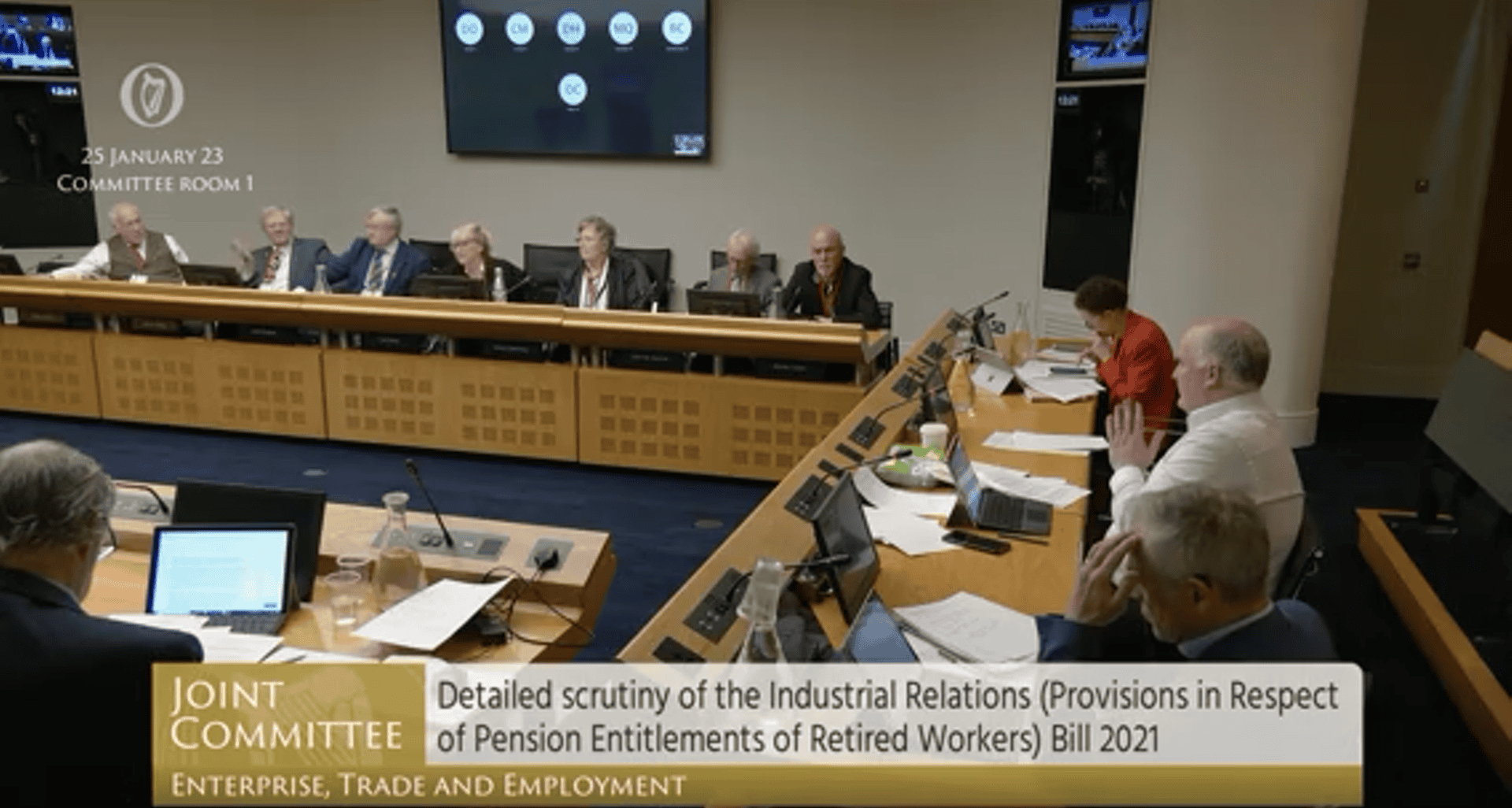 Image of senior representatives and officials in a formal committee meeting on pension legislation.